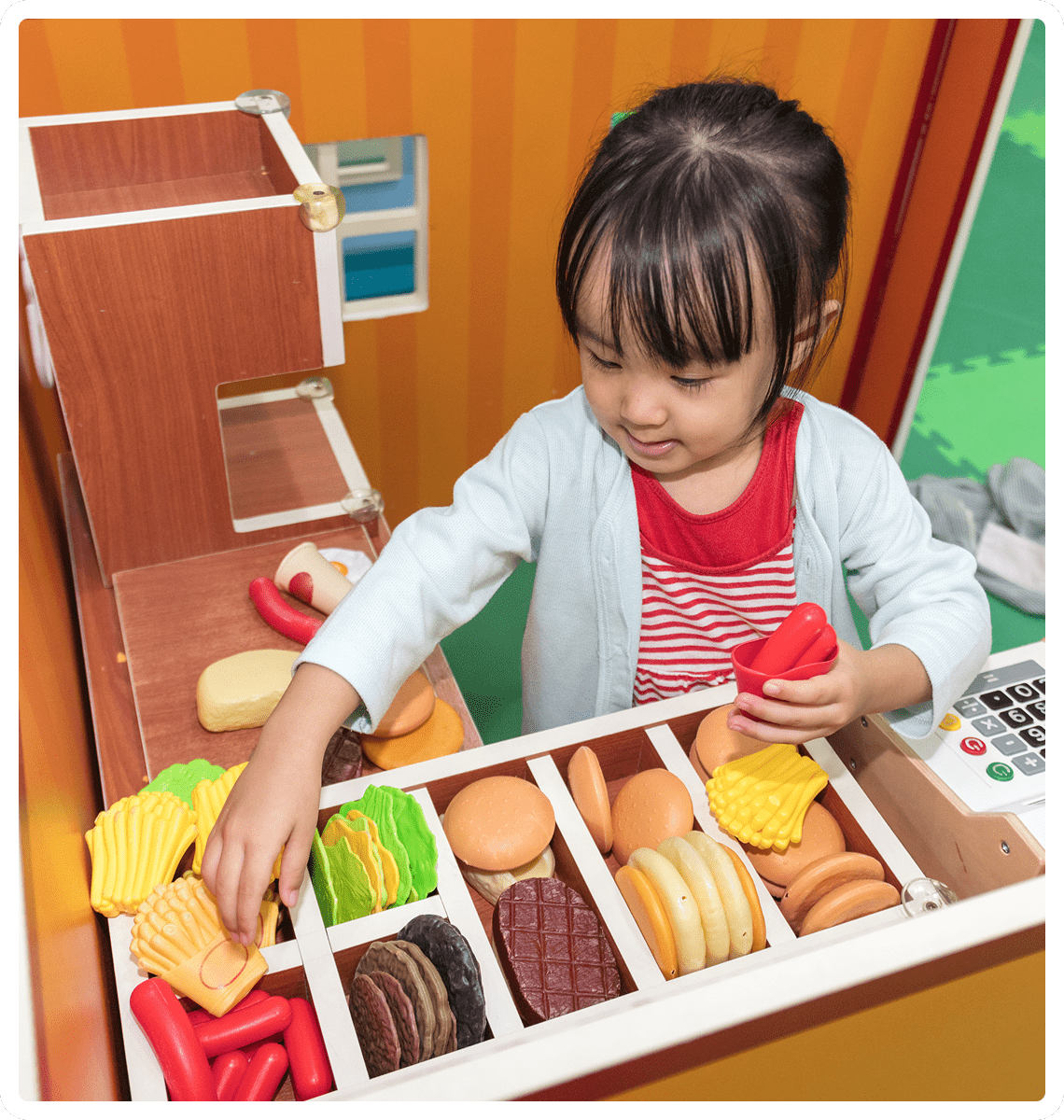 Girl arranging toy snacks in play kitchen