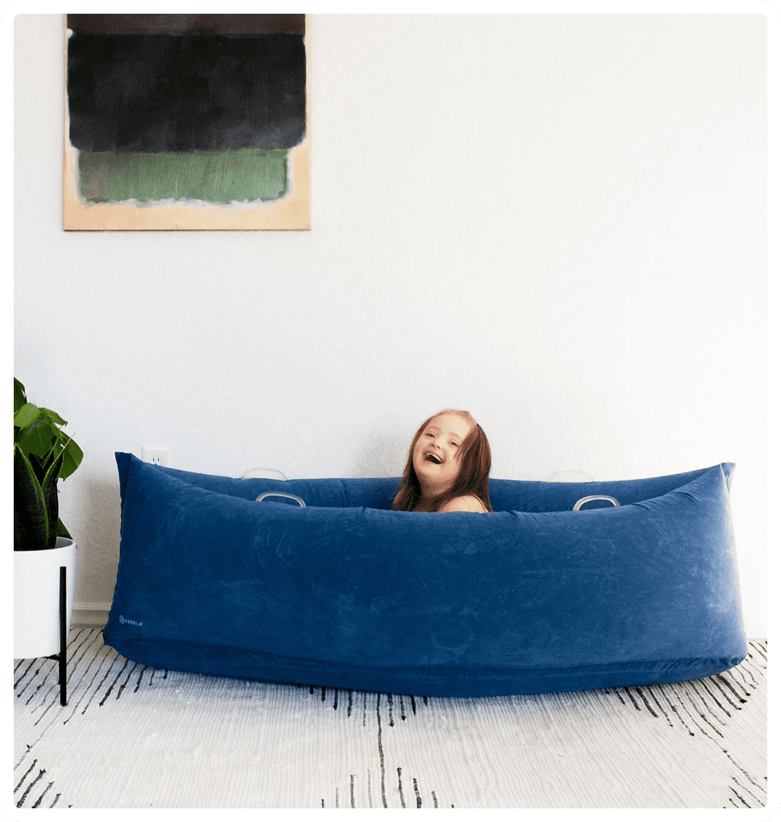 Child laughing inside a large blue cushion.